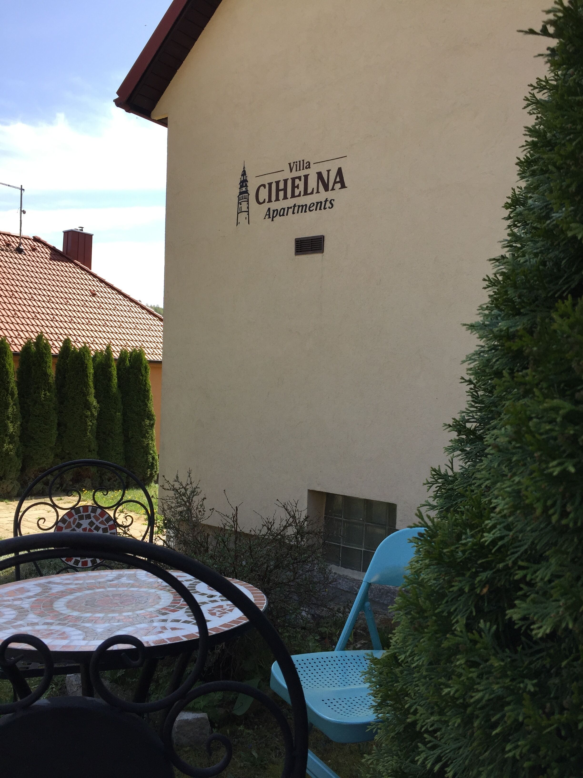 Villa Cihelna Apartments with a tiled roof, outdoor seating, and a wall-mounted sign.