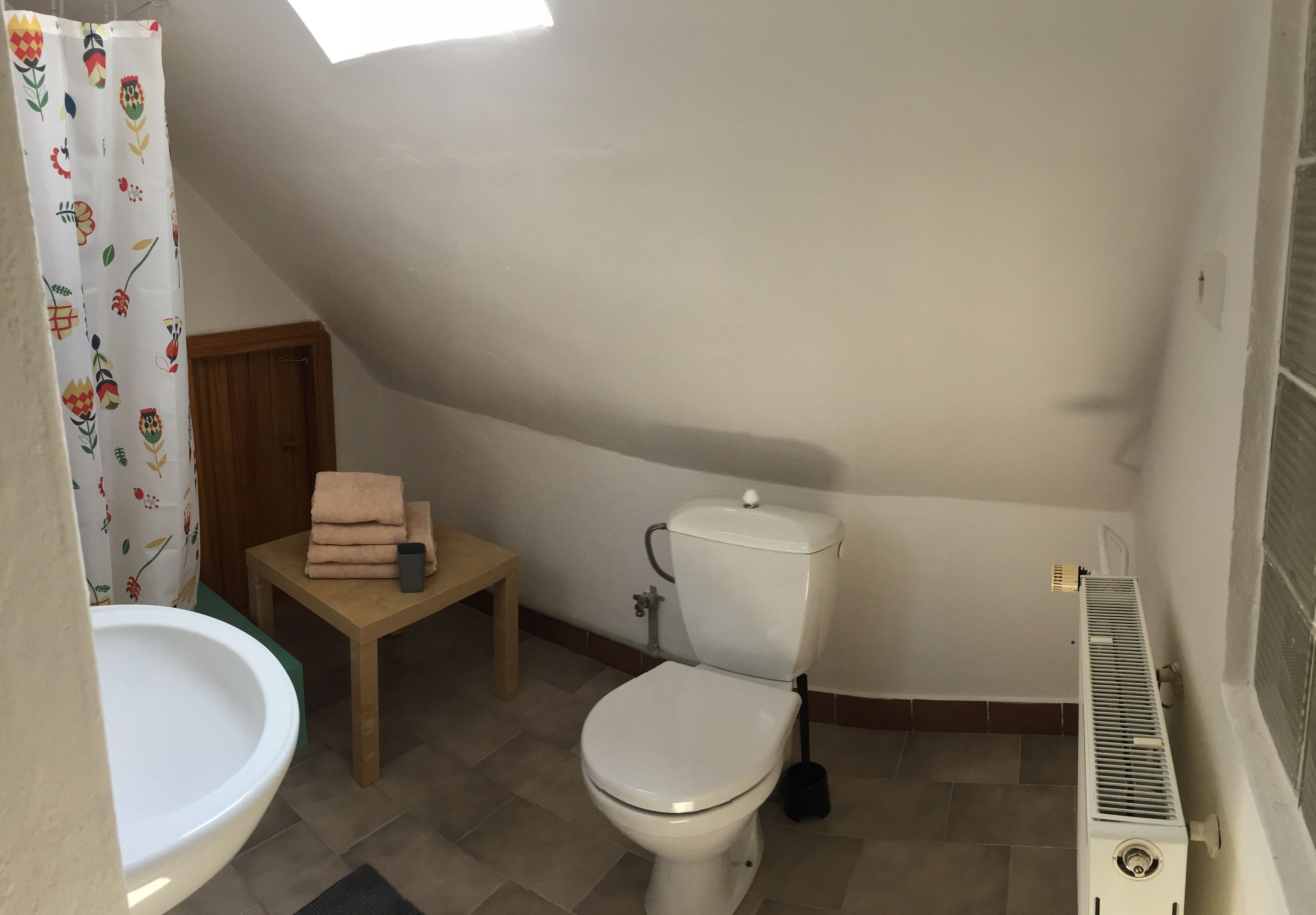 Een kleine, compacte badkamer met toilet, wastafel en douchegordijn.