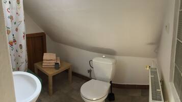 Een kleine, compacte badkamer met toilet, wastafel en douchegordijn.