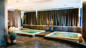 A spa area with two hot tubs, dark curtains, and two golden Buddha statues. - Hotel Up Museum - Wellness & Spa (Foggia)