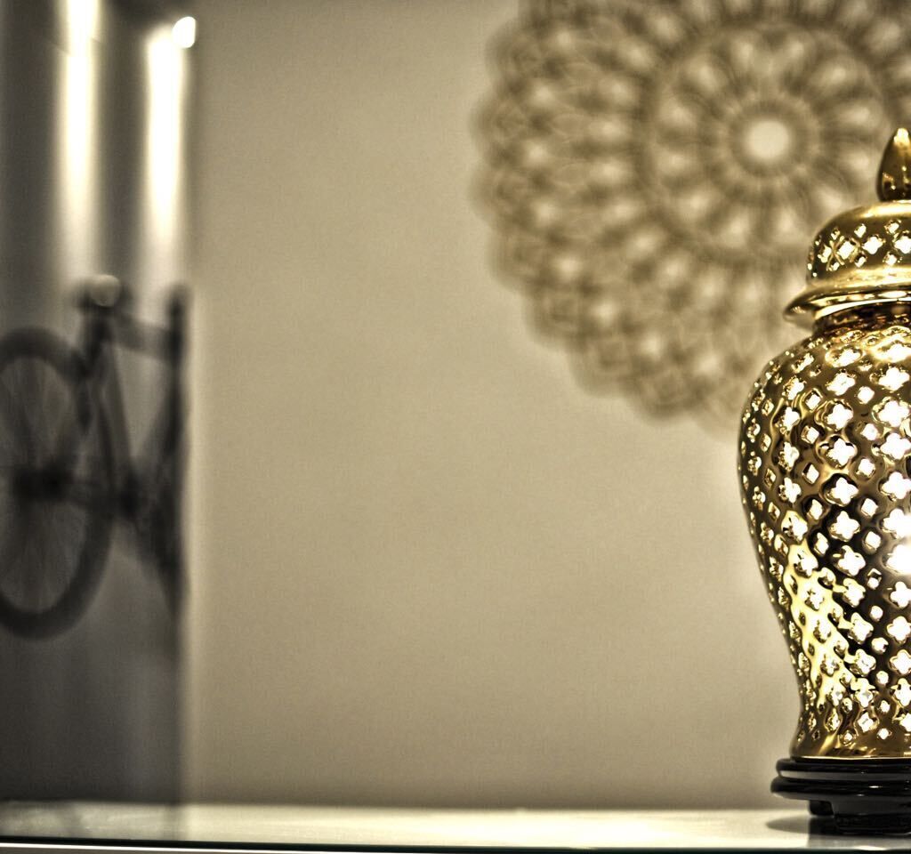 A decorative gold vase on a table with a bicycle in the background.