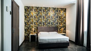 Ein modernes Schlafzimmer mit einem großen Bett, zwei Nachttischen mit Lampen, einer gemusterten Tapete und einem dunklen Boden.