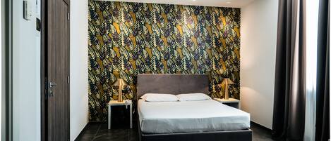 Un dormitorio moderno con una cama grande, dos mesitas de noche con lámparas, un papel tapiz estampado y un suelo oscuro.