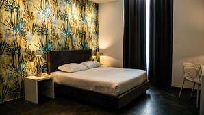 A modern bedroom with a large bed, two bedside lamps, a nightstand, a chair, and a patterned wallpaper. - Hotel Up Museum - Wellness & Spa (Foggia)
