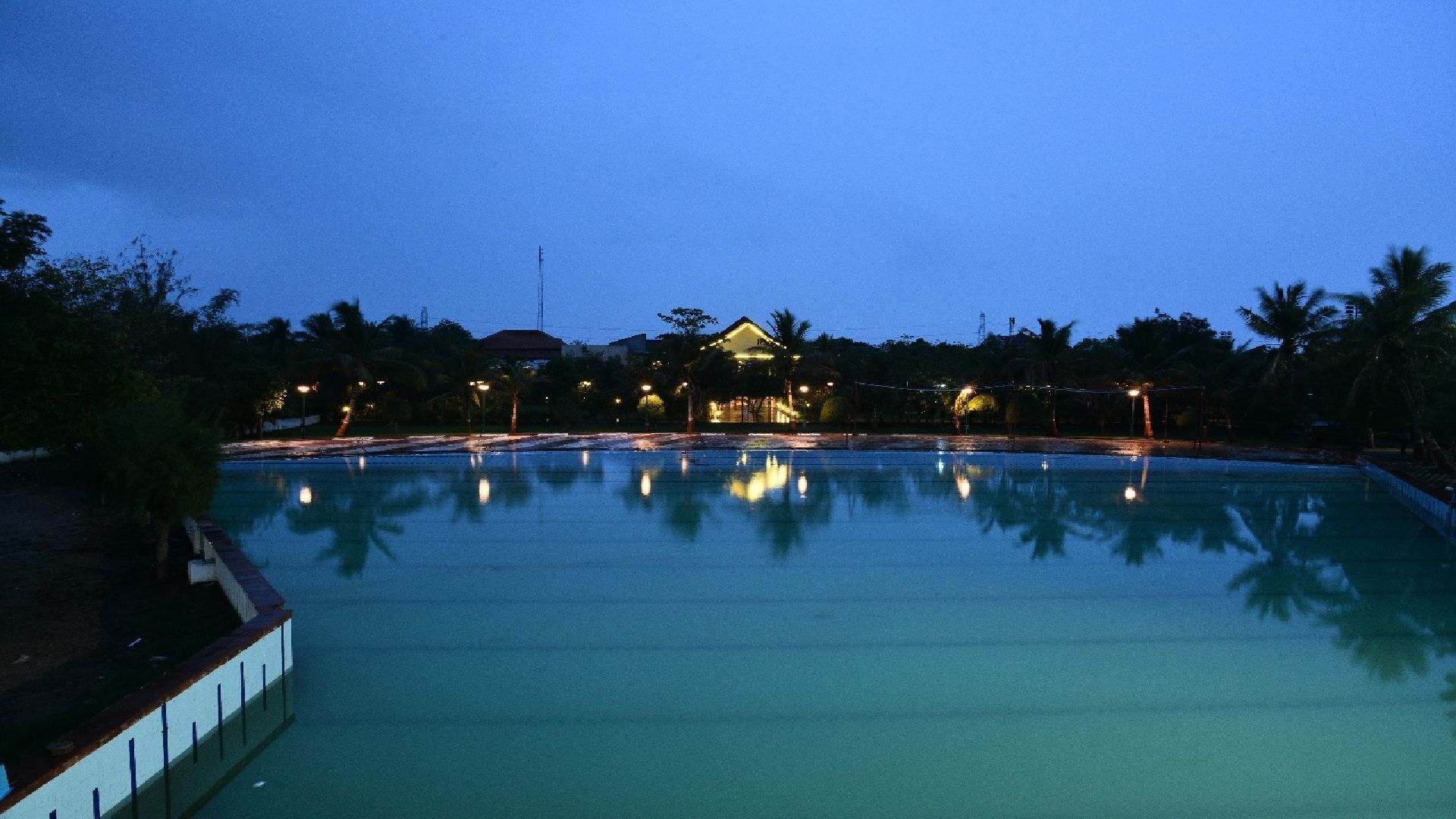 Uma piscina ampla e tranquila, refletindo um edifício e árvores.