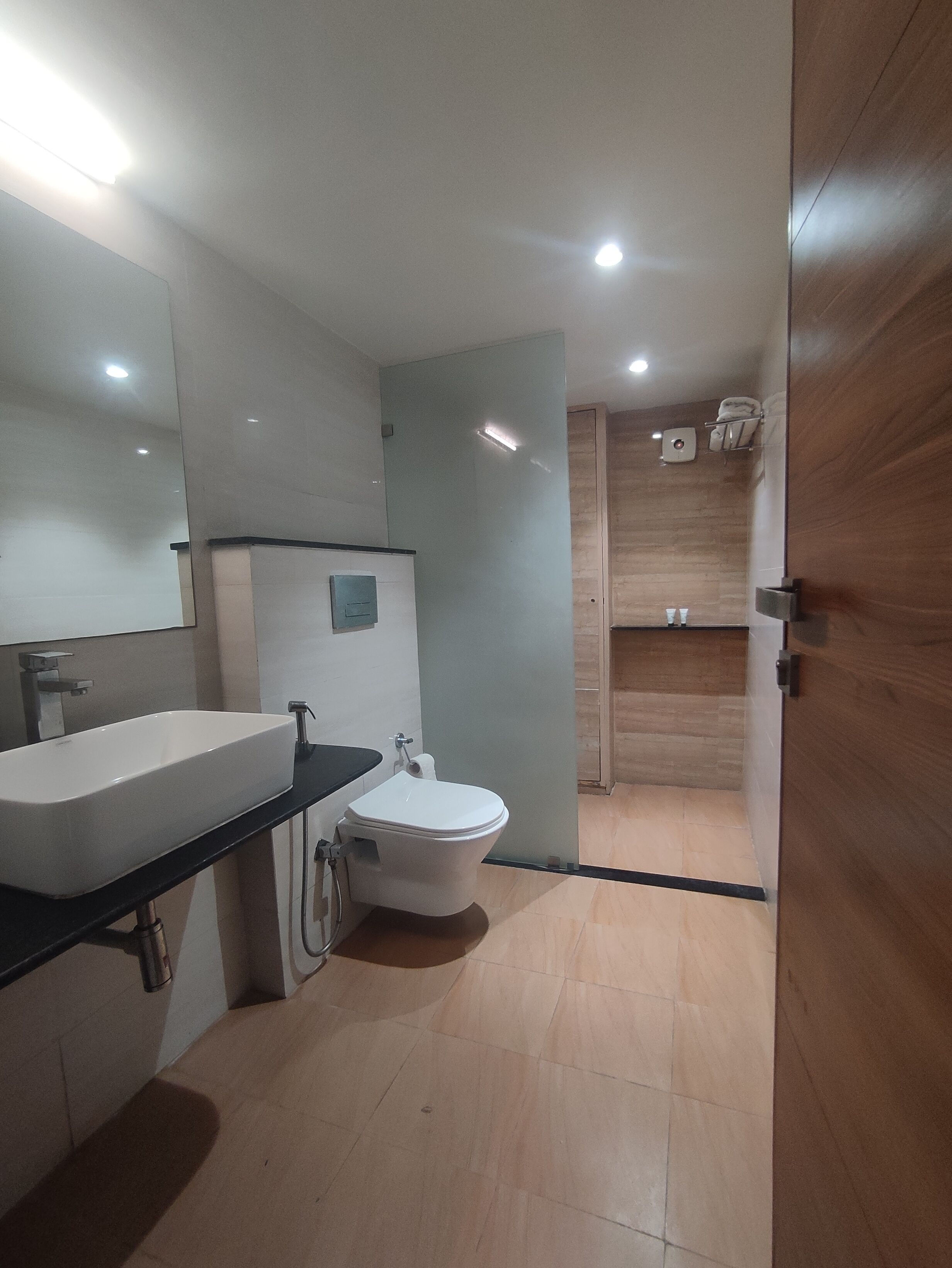 A modern bathroom with a large mirror, a sink, a toilet, and a shower area.