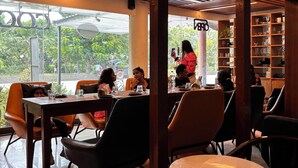 An indoor dining area with tables and chairs, large windows, and a wooden ceiling. - Palm Green Club & Resort by The Sky Imperial (Kheda)