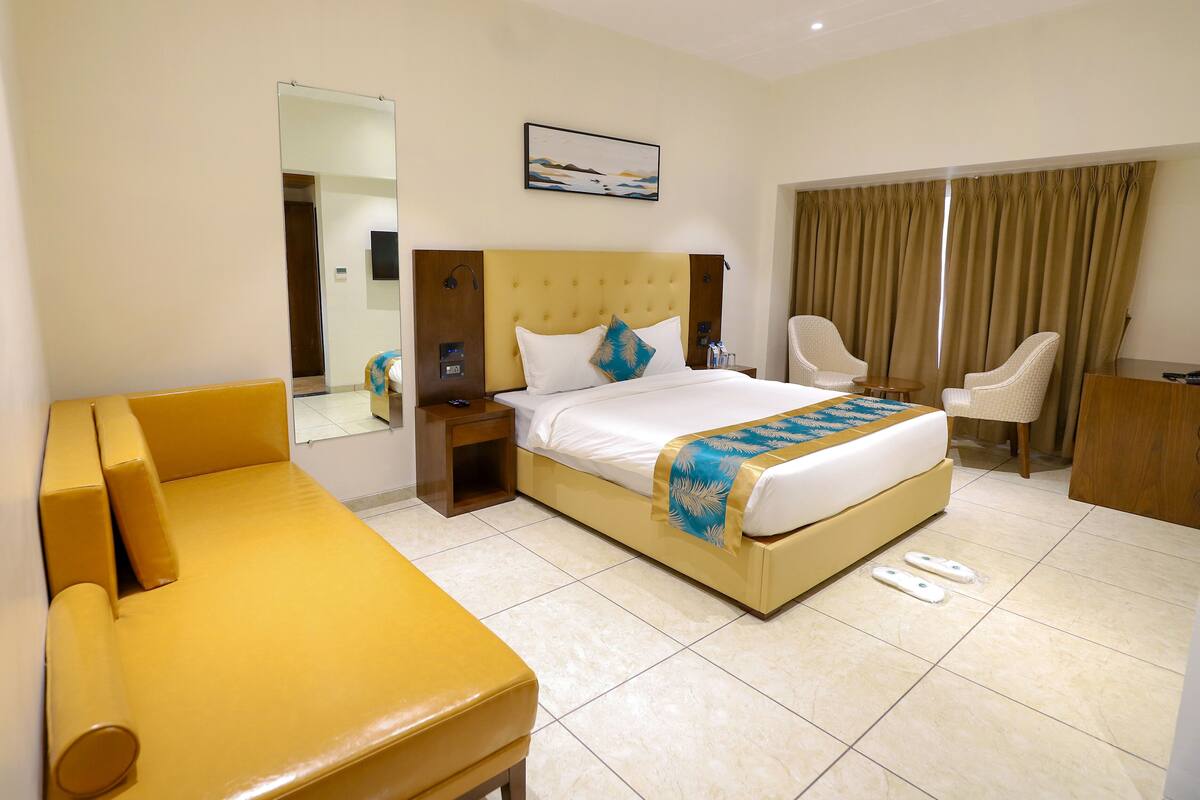 A hotel room with a bed, a sofa, a desk, and a chair.