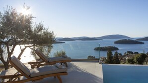 A poolside area with lounge chairs and a view of a lake with islands. - Elegant stone-built Villa, with heated pool and amazing view (Lefkada)