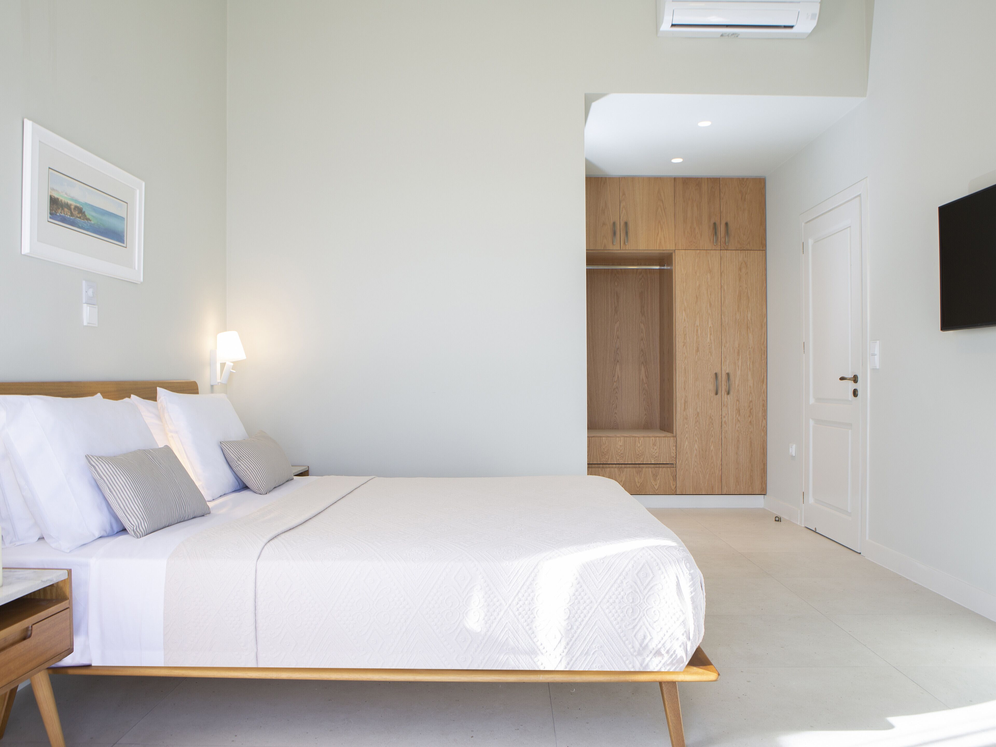 A modern bedroom with a bed, bedside table, and a wardrobe.