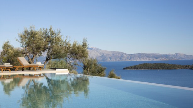 An infinity pool with lounge chairs and a view of the sea and mountains. - Elegant stone-built Villa, with heated pool and amazing view (Lefkada)