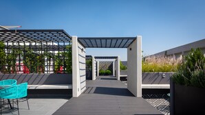 A rooftop patio with a pergola, outdoor seating, and a view of the cityscape. - NIU Modern & Centric Lofts (Mexico City)