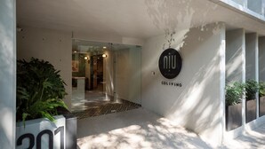 A modern building entrance with a glass door, a sign reading "niu COLLIVING", and a planter with the number "301". - NIU Modern & Centric Lofts (Mexico City)