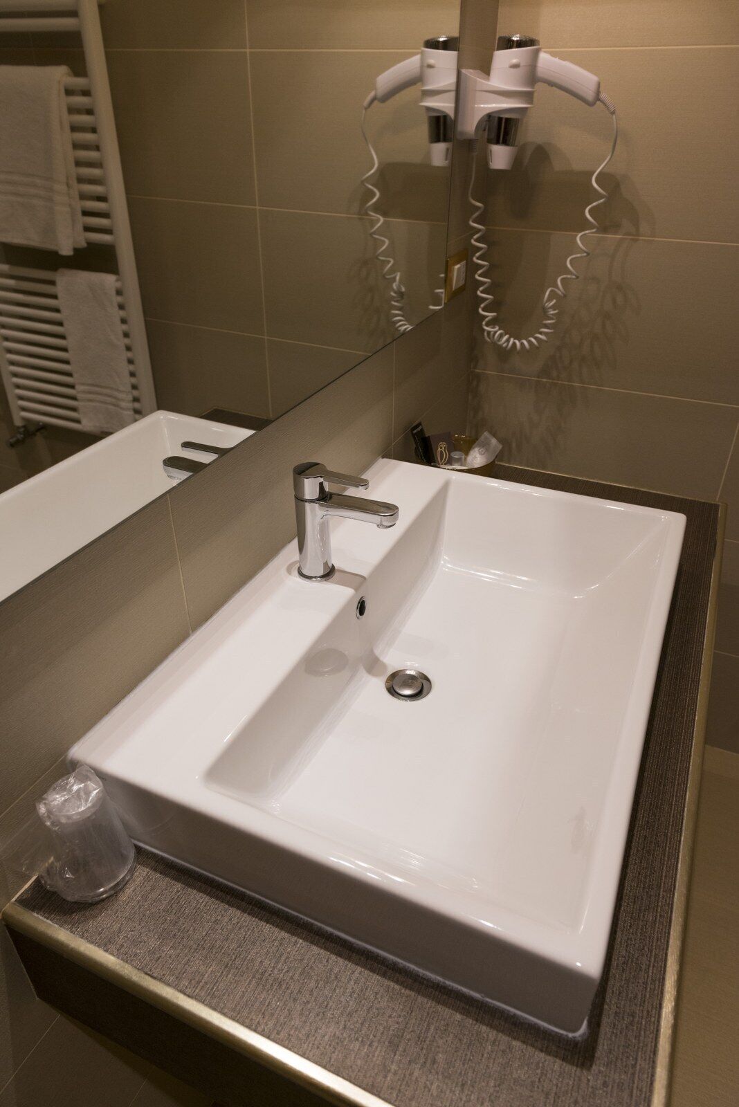 Ein modernes Badezimmer mit einem weißen Waschbecken, einem Spiegel und einem Handtuchhalter.