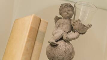 A statue of a cherub holding a glass, with a book in the background.