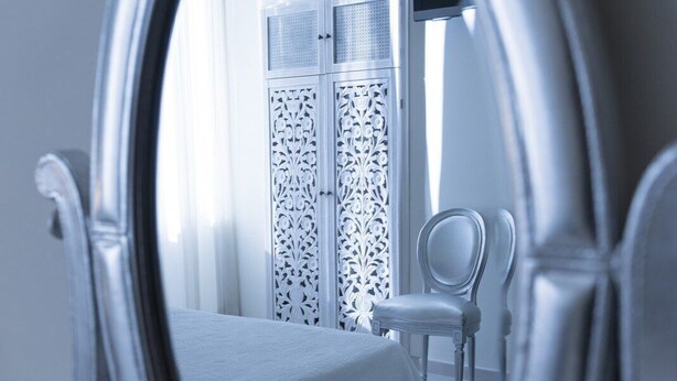 Un dormitorio con cama, una silla y un armario de diseños elaborados.