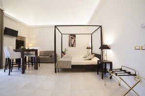 Um quarto moderno com uma cama de dossel, uma escrivaninha com cadeira, um sofá e uma mesa de cabeceira com abajur.