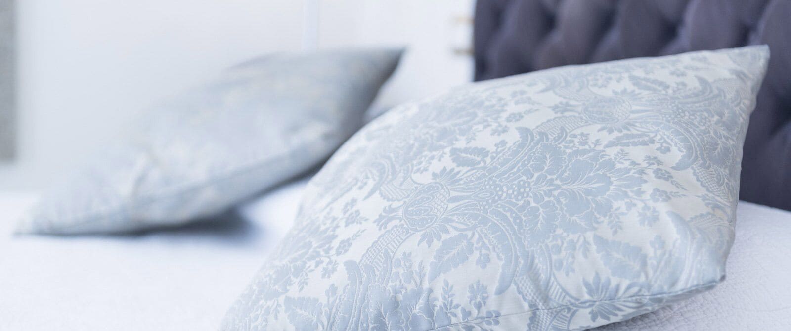 A bed with two pillows featuring a floral pattern.