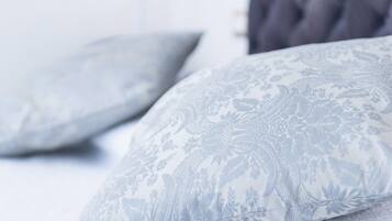 A bed with two pillows featuring a floral pattern.