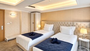 Een hotelkamer met twee bedden, een kledingkast, een bureau en een lamp.