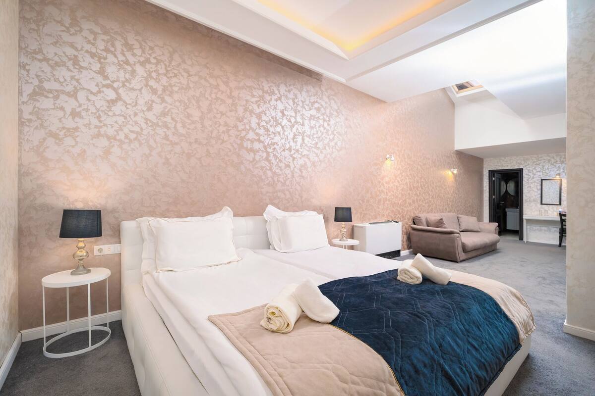 A hotel room with a large bed, a sofa, a desk, and a chair.