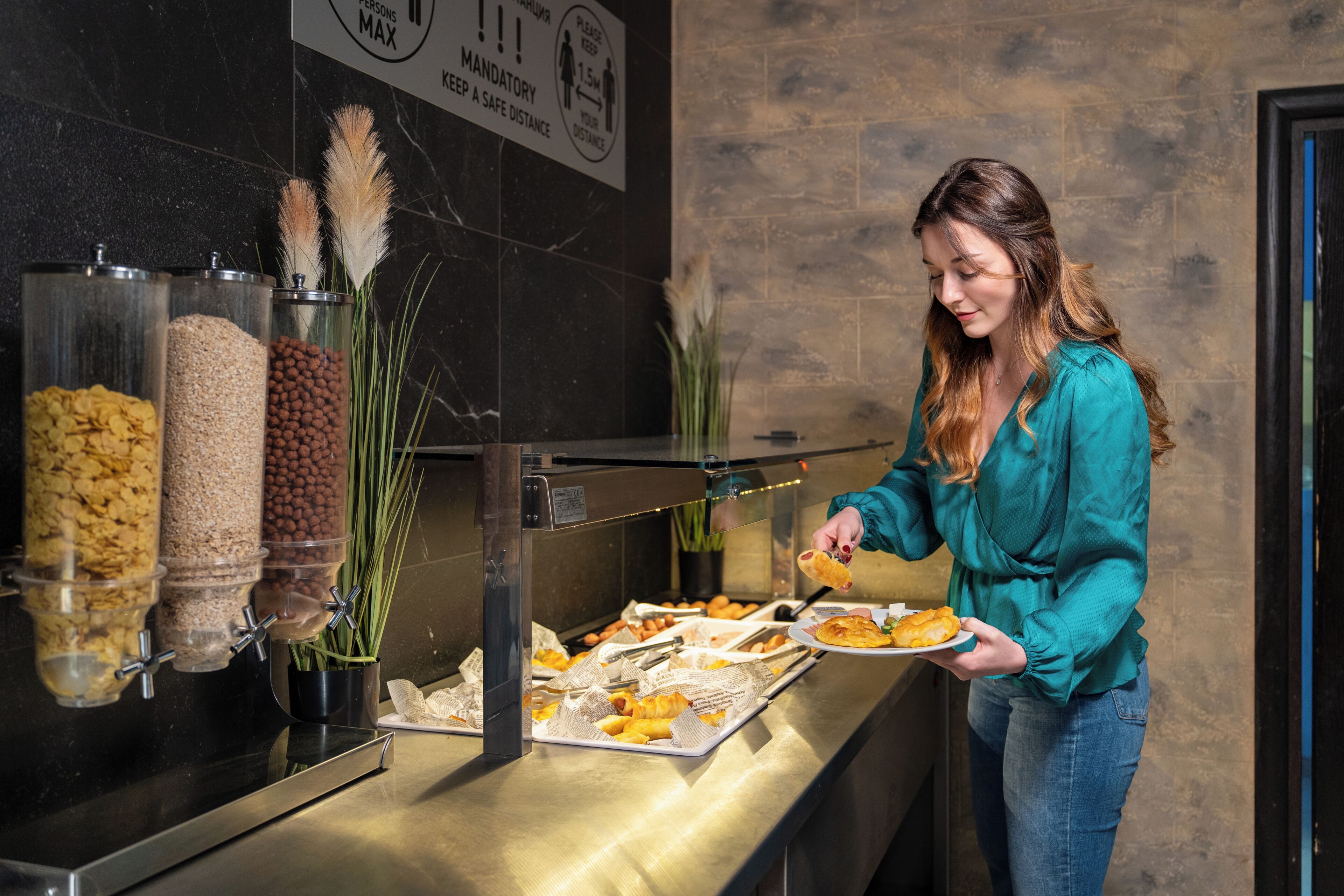 Een buffet met diverse voedselcontainers en iemand die zich bedient.