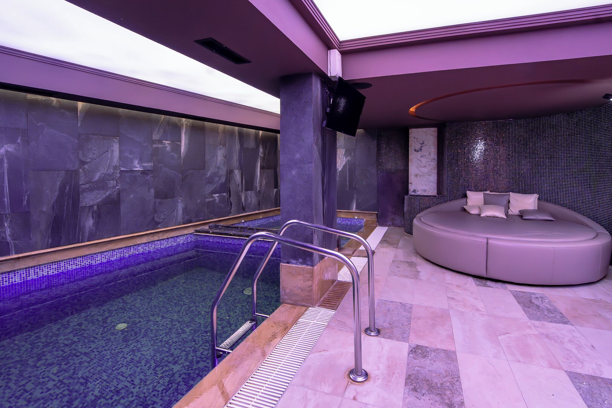 A spa area with a pool, a seating area, and a stone wall.