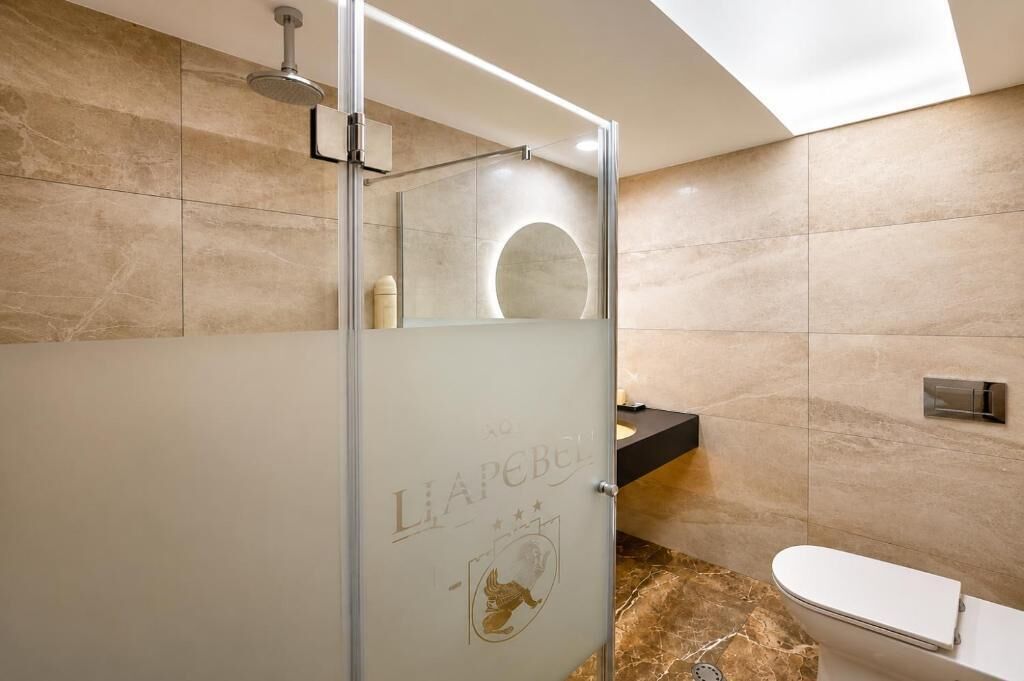 A modern bathroom with a glass-enclosed shower, a toilet, and a sink.