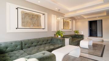 A spacious living area with a green sectional sofa, a white coffee table, and a chandelier.