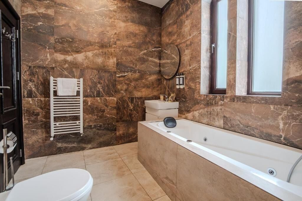 Un baño con bañera, inodoro y un perchero para toallas.
