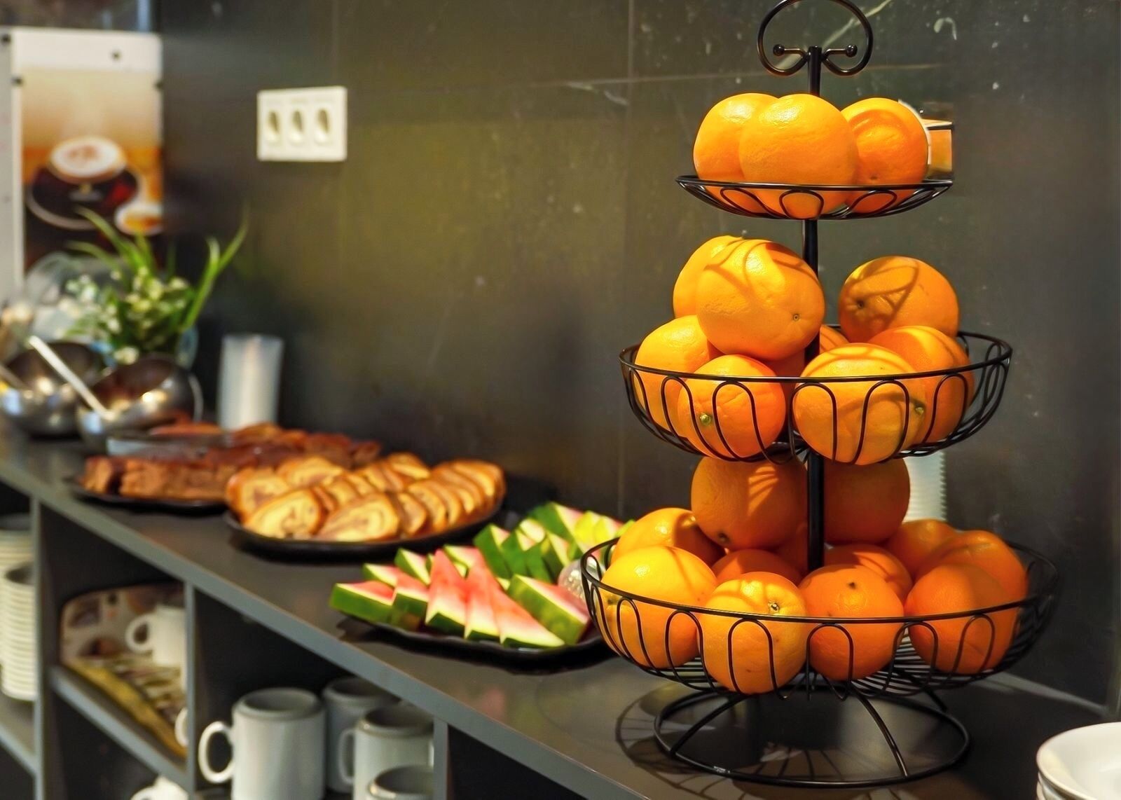 Un bufé con una mesa de frutas de tres niveles y una presentación de sandía en rodajas.