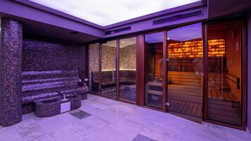 A spa area with a mosaic wall, a seating area, and a wooden sauna.