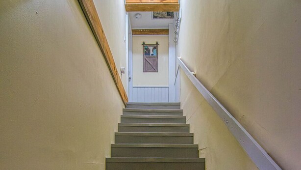 A staircase with a handrail on one side and a wall on the other, leading to a door at the top. - Easy access to VAST snowmobile trail system and local mountain bike trails (Randolph Center)