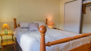 A bedroom with a wooden bed, two bedside lamps, a nightstand, and a closet. - Easy access to VAST snowmobile trail system and local mountain bike trails (Randolph Center)