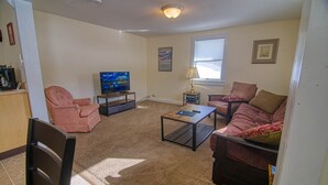 A living room with a sofa, armchair, coffee table, and a television. - Easy access to VAST snowmobile trail system and local mountain bike trails (Randolph Center)