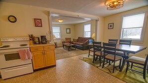 A kitchen with a stove, cabinets, and a dining area with chairs and a table. - Easy access to VAST snowmobile trail system and local mountain bike trails (Randolph Center)