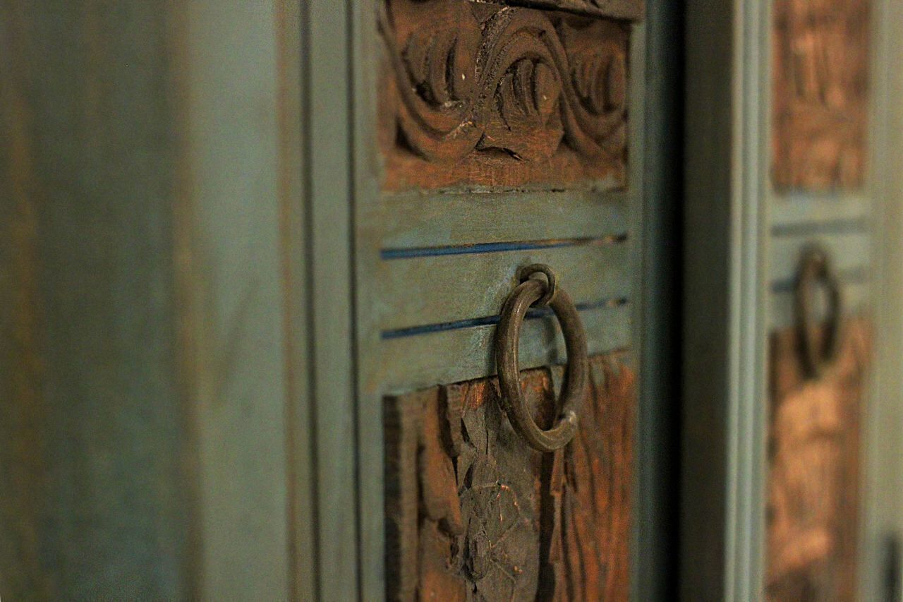 A close-up of a wooden door with intricate carvings and a metal ring handle.