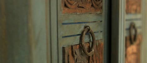 Um close-up de uma porta de madeira com detalhes entalhados e um puxador em metal.