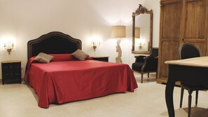 Un dormitorio con una cama grande, un armario de madera, un escritorio y dos mesitas de noche.