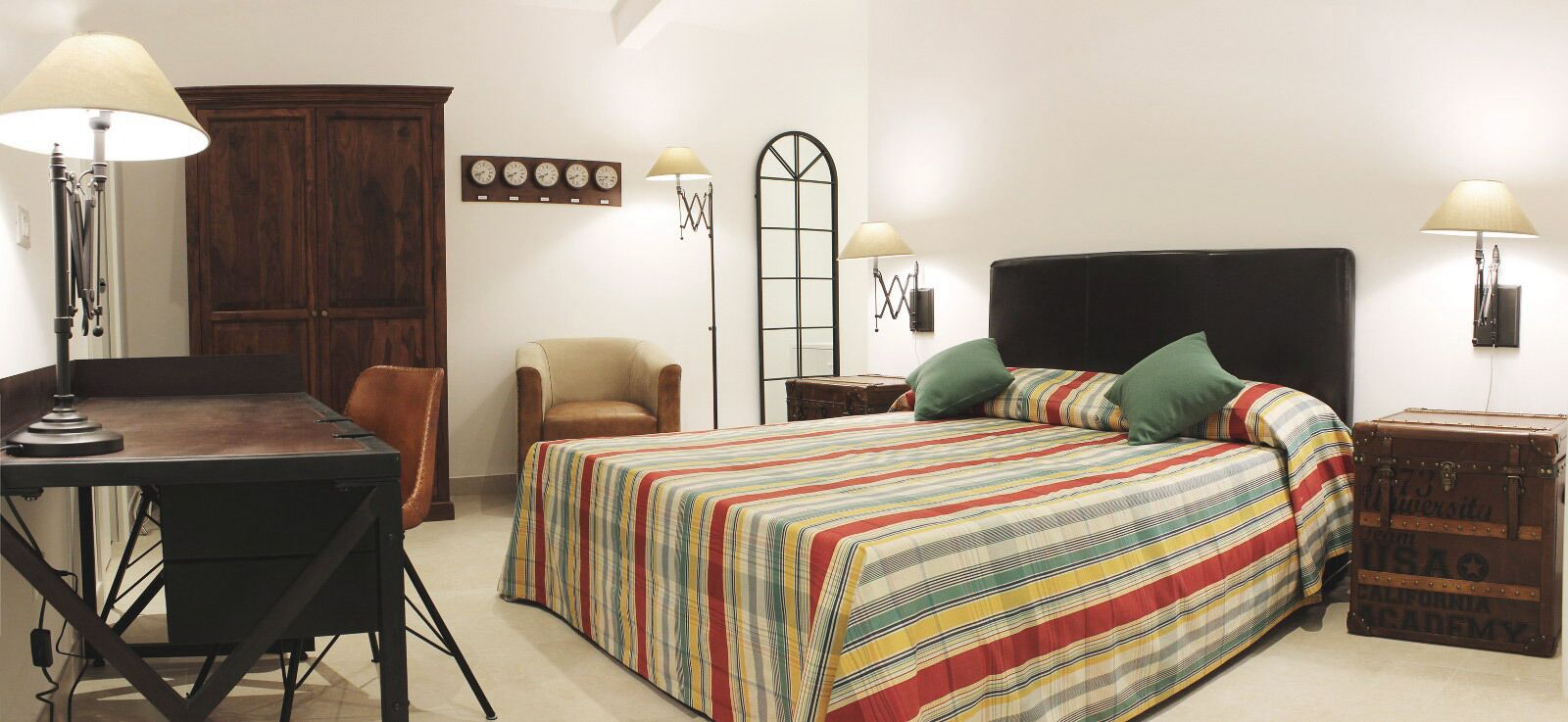 Une chambre à coucher avec un lit, deux chaises, un bureau et une armoire.