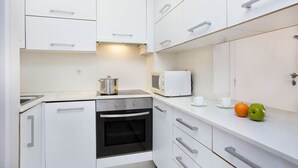 Una cocina moderna con armarios blancos, horno empotrado, microondas y un lavabo.