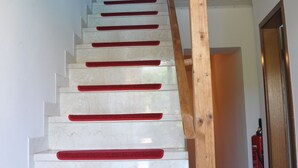 Una escalera con alfombras rojas y barandilla de madera.