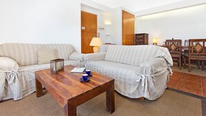 A living room with striped sofas, a wooden coffee table, and a dining area with wooden chairs and a table. - 1SARR 01 - Apartment for 4 people  located in Llafranc only 170m from the beach (Llafranc)