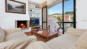 A living room with a fireplace, a television, and a large window with a view of the city. - 1SARR 01 - Apartment for 4 people  located in Llafranc only 170m from the beach (Llafranc)