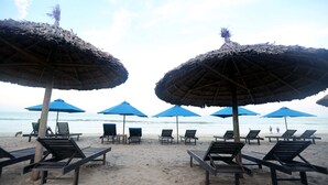 A beach with thatched umbrellas and lounge chairs. - Tan Doan An Bang center beach villas (Tp. Hội An)
