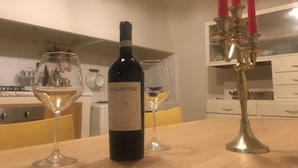 Een fles wijn op een tafel met twee glazen en een kandelaar met kaarsen.