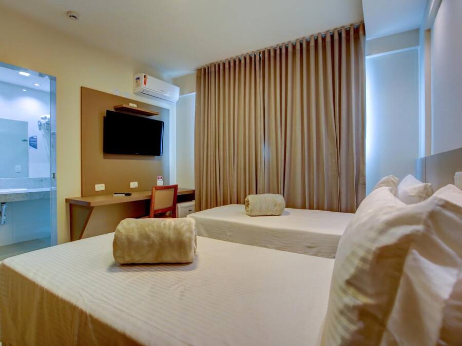 Habitación de hotel con dos camas, un escritorio, un televisor y un baño.