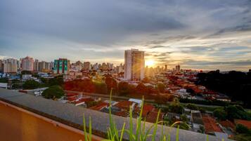 Un paisaje urbano con un rascacielos destacado y un atardecer.
