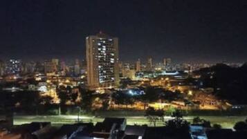 Paesaggio urbano notturno con edifici illuminati e un'imponente struttura alta al centro.