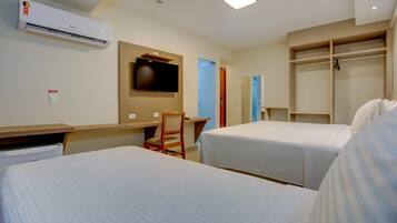 A hotel room with two beds, a desk, a chair, a TV, and a wardrobe.